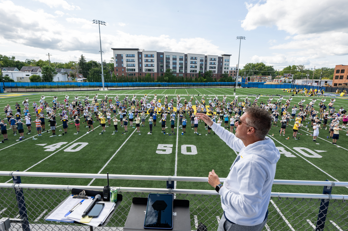 Photo of John Pasquale, director of Michigan Marching and Athletic Bands, leading the band in a rehearsal at its new Elbel Field practice facility.