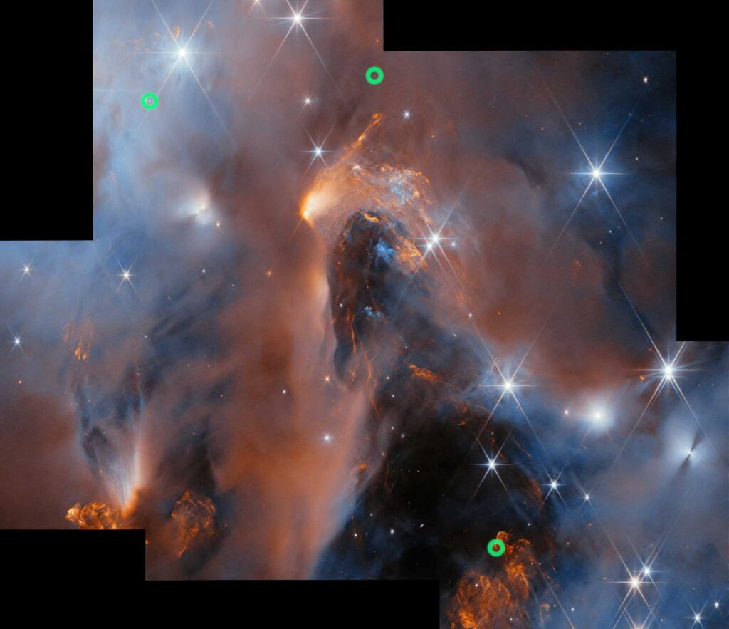 Several images of parts of a nebula in space have been aligned to form a single large image of the nebula. It depicts clouds of gas and dust in blue and orange colors as well as brightly shining stars in various sizes. Around the edge there are some black rectangles where there was no image of that region of space.