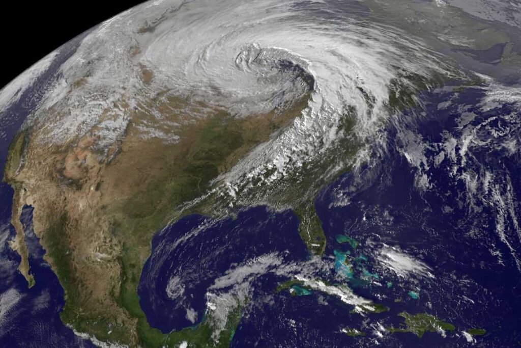 A composite satellite image shows North America, with Mexico easily visible against a deep blue sea. The northern U.S. and Canada are hidden, however, under dense white clouds, swirling around an extratropical cyclone center above Minnesota.