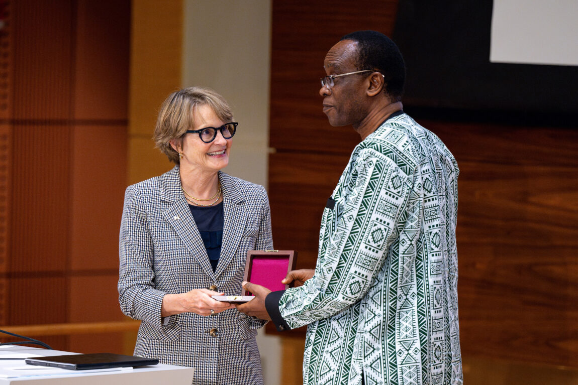 A photo of a woman handing a man a medal