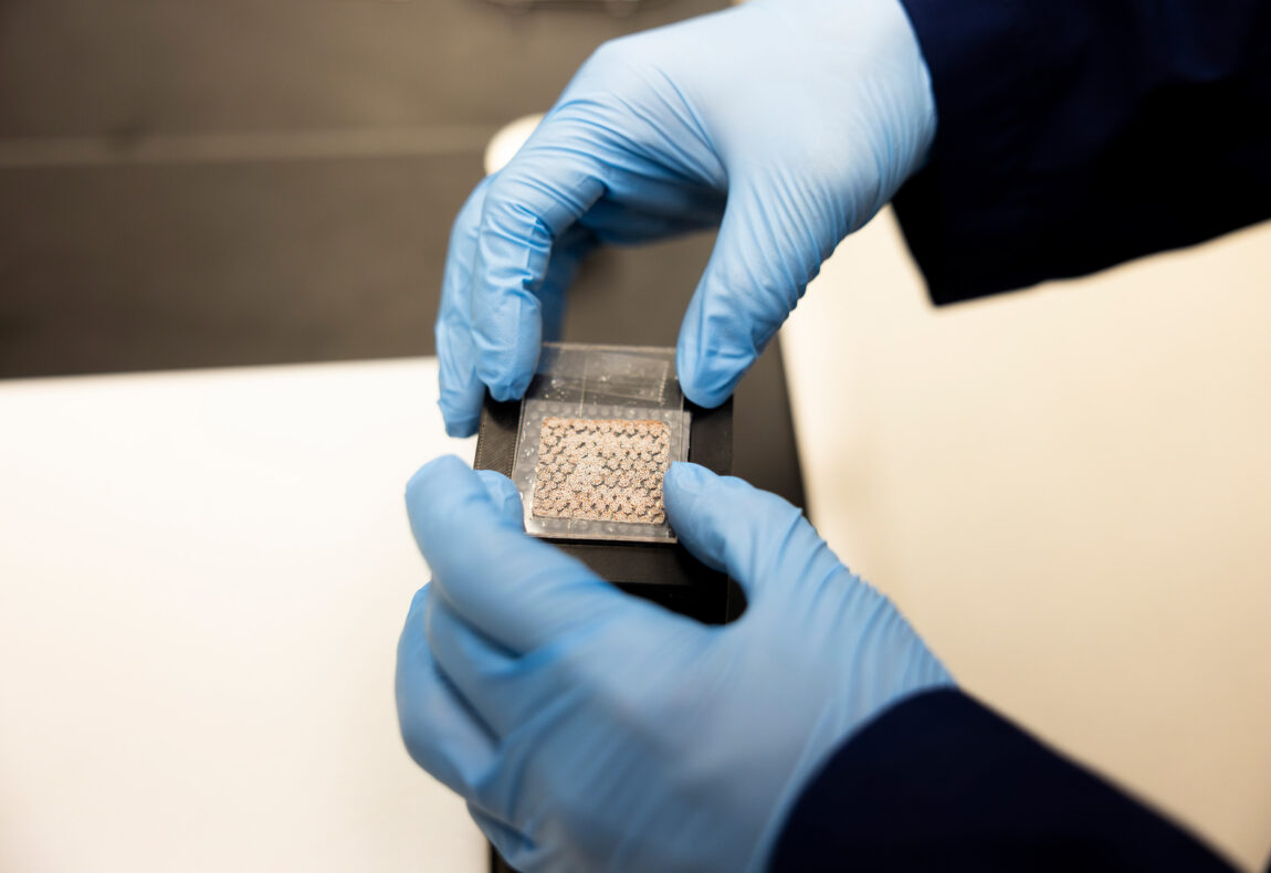 Gloved hands hold a small screen that uses magnets to display the image