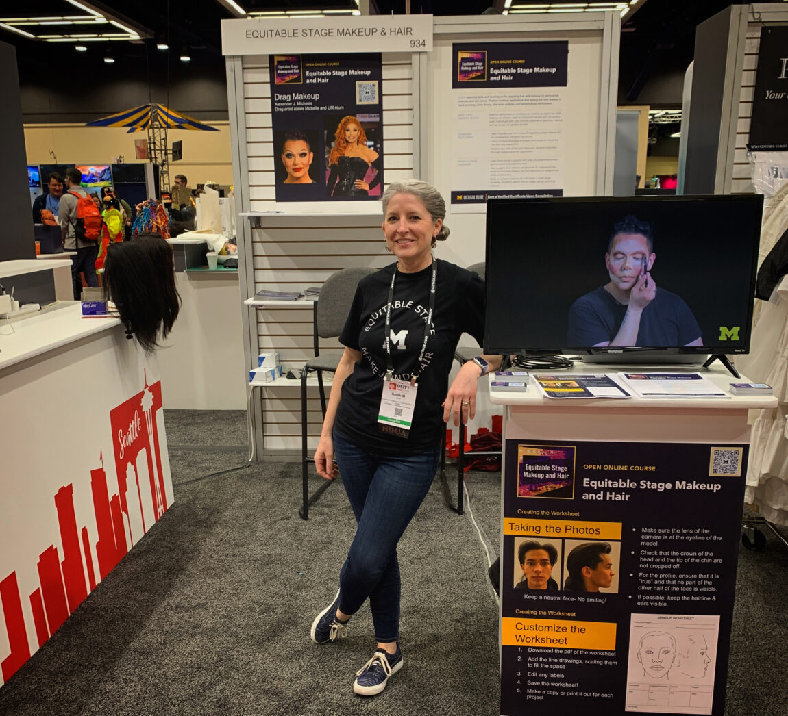 A photo of a woman leaning on a display table at a trade show