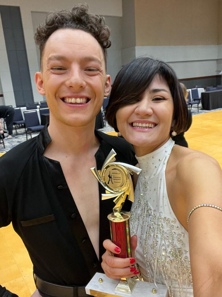 A photo of a man and woman smiling and holding a trophy