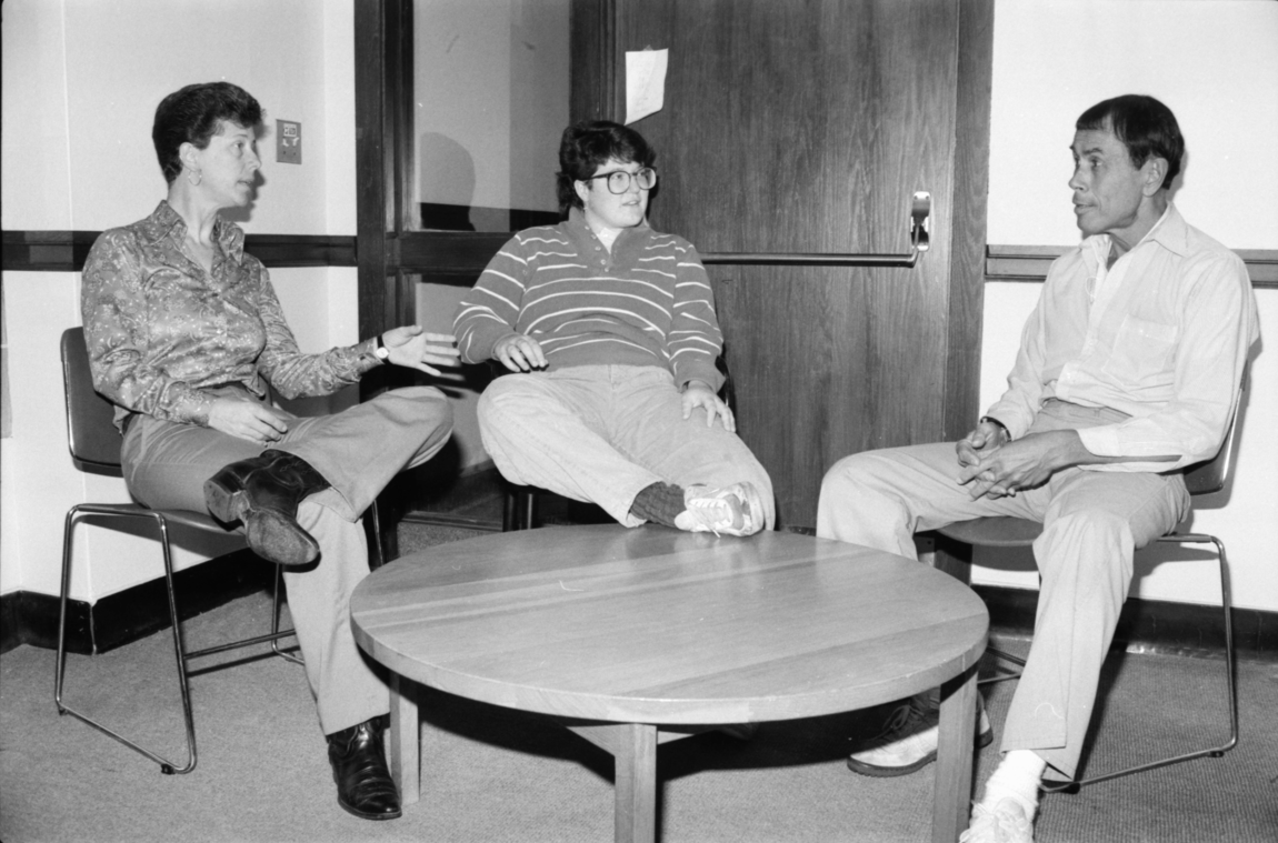 A photo of three people sitting around a small table
