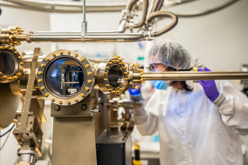 In the background, Pan shines a light into the device. In the foreground are multiple portholes and tubes in silvery metal.