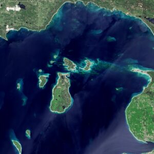 Beaver Island is a large green mass surrounded by the dark blue waters of Lake Michigan. Smaller islands surround Beaver Island to the north and west.