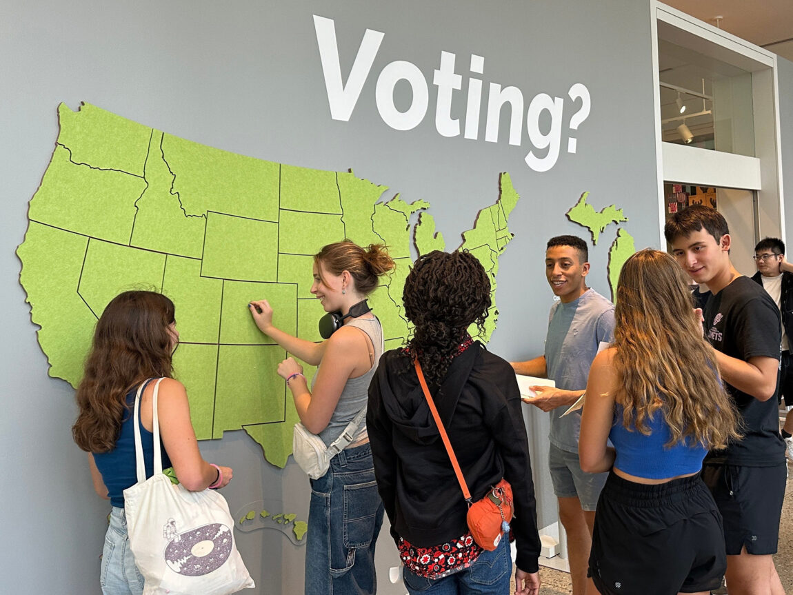 A photo of several people standing near a map of the United States
