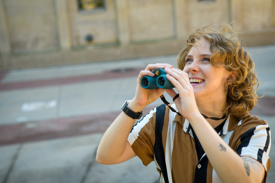 A photo of a person holding binoculars and looking at the sky
