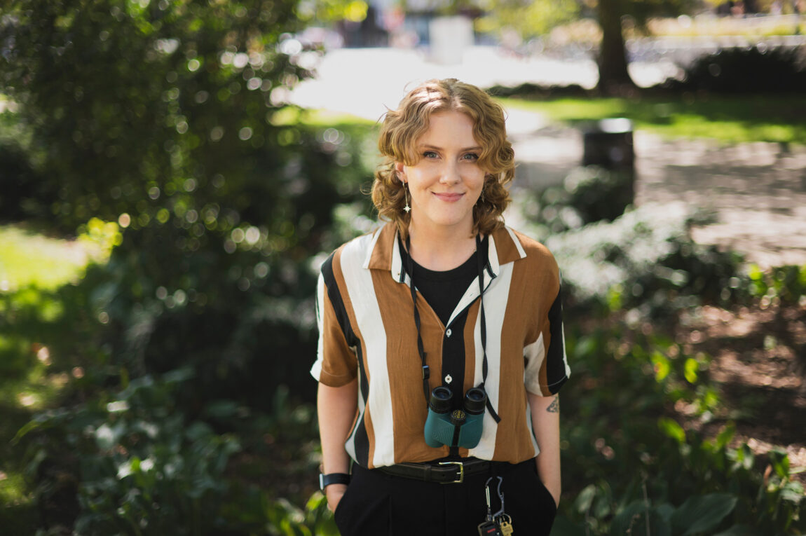 A photo of a person smiling while wearing binoculars