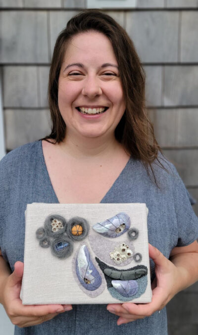 A photo of a woman holding a piece of fiber art