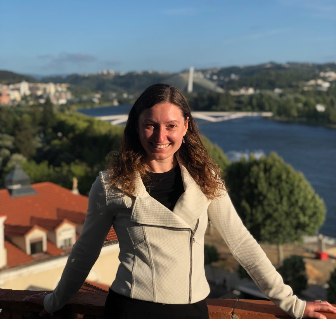 A photo of a woman standing on a deck overlooking a body of water