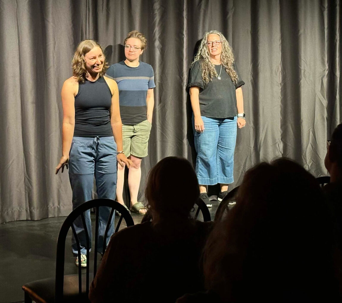 A photo of three women performing an improv show