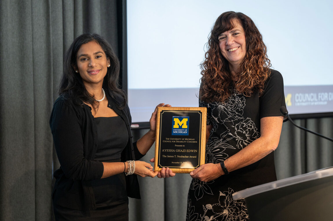 Photo of two women holding a plaque.