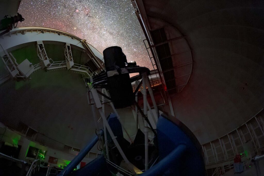 A view inside the dome of the Nicholas U. Mayall 4-meter Telescope. The dome is opened, revealing a strip of night sky filled with stars for DESI to observe.