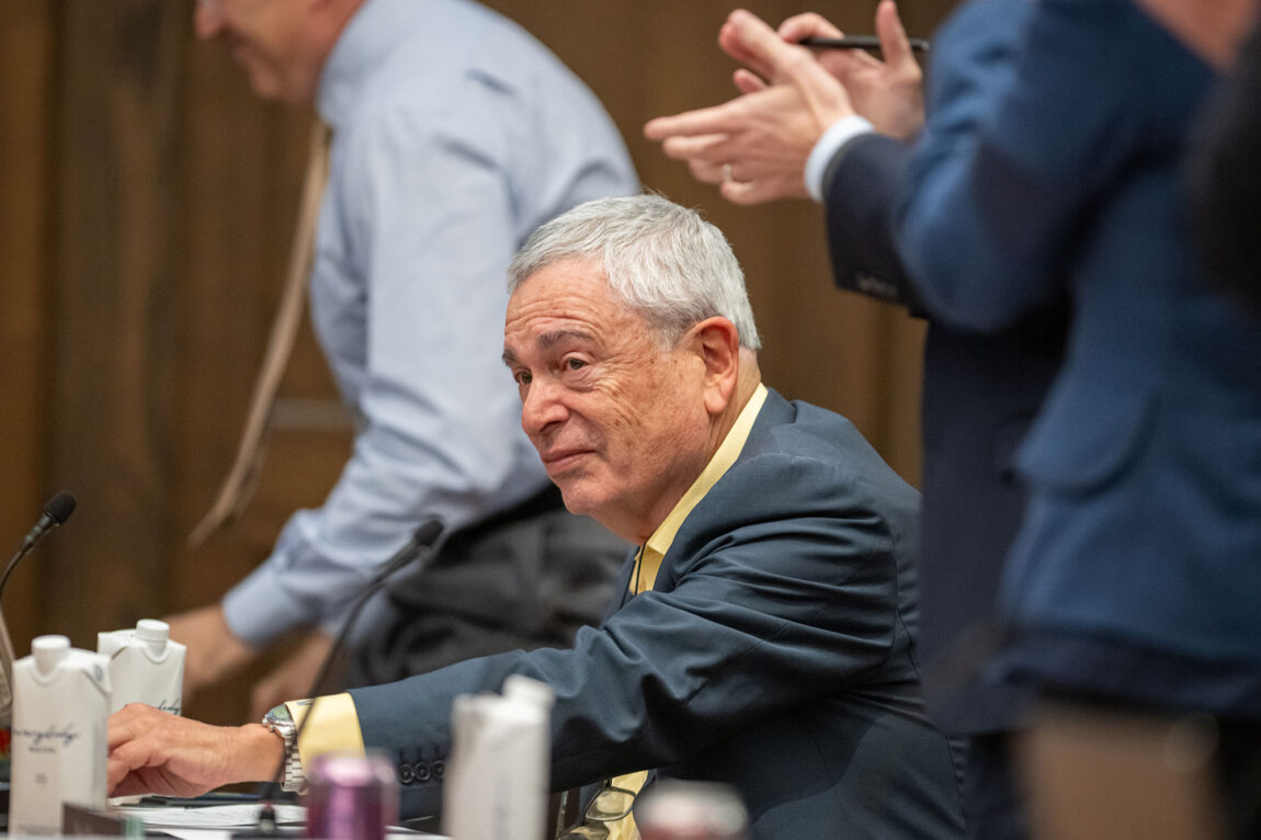 Photo of Ron Weiser sitting and accepting applause from others.
