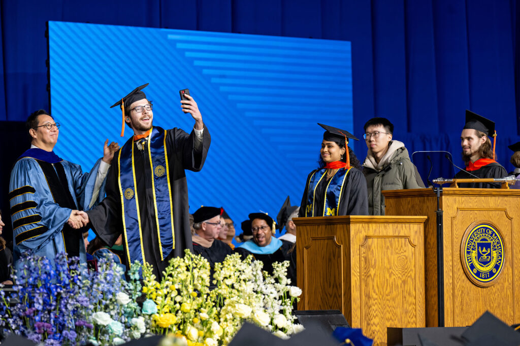 Photo of a graduate takinga selfie with President Ono.