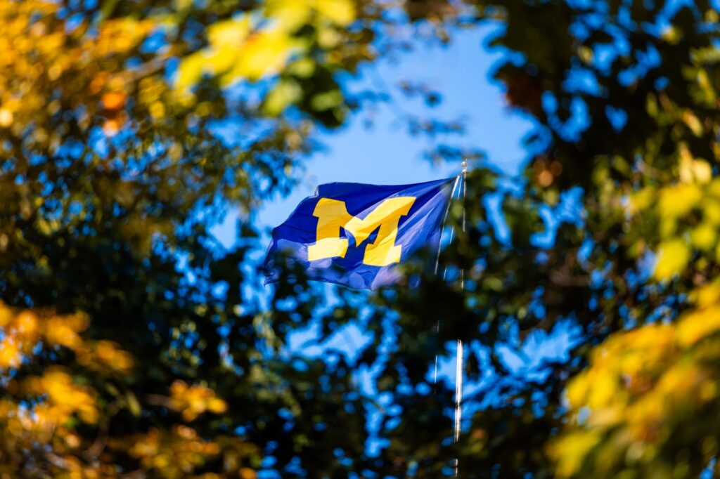 The Michigan Union Flag framed by vibrant fall leaves.