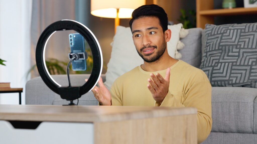 Influencer recording a video on a phone at home. Young man creating content and live streaming a broadcast online for a vlog channel. Guy filming a podcast while speaking to followers on social media Image credit: Jacob Wackerhausen, iStock