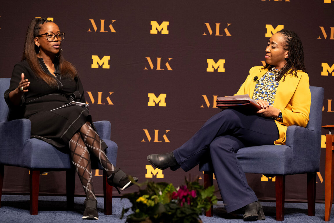 Photo of two women talking while sitting in chairs on stage