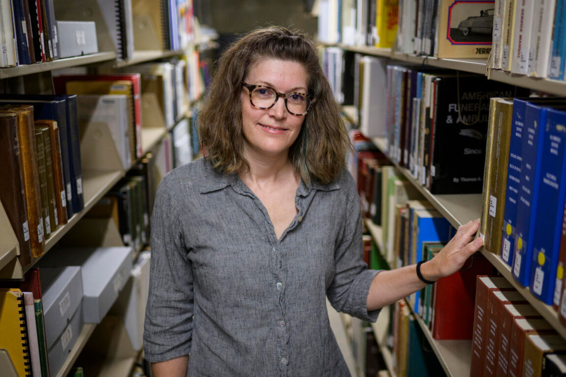 Photo of a woman standing in row of books in a library