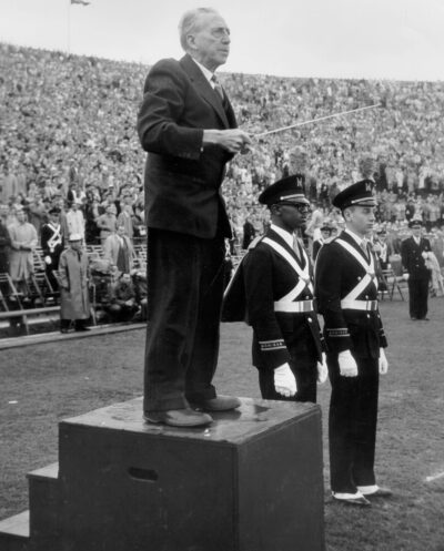 A photo of a man conducting the Michigan Marching Band