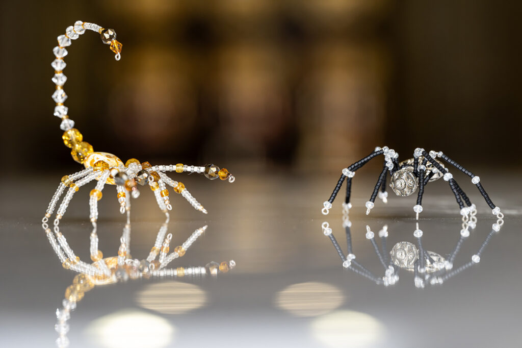 A photo of two pieces of jewelry made from beads that resemble a scorpion and a spider
