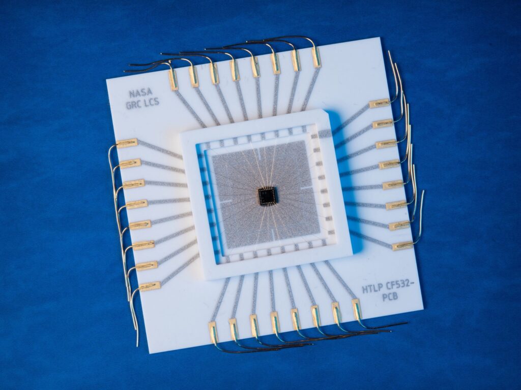 A black square at the center of a series of larger and larger lighter squares. Bands of thin metallic lines radiate outward from the center in a pattern that resembles a flower with four petals. The device is set on a blue background.