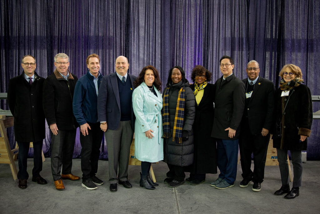A photo of several people standing side by side after signing a beam for a construction project