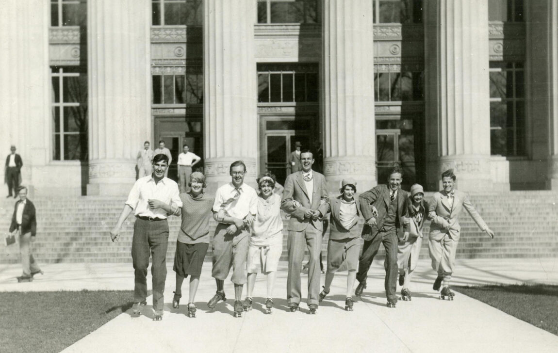 A photo of people rollerskating in front of a building in 1927