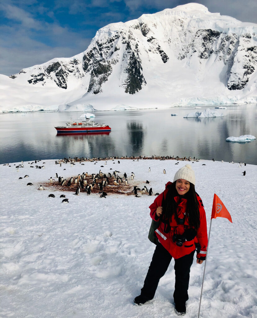A woman standing in Antarctica with penguins in the background