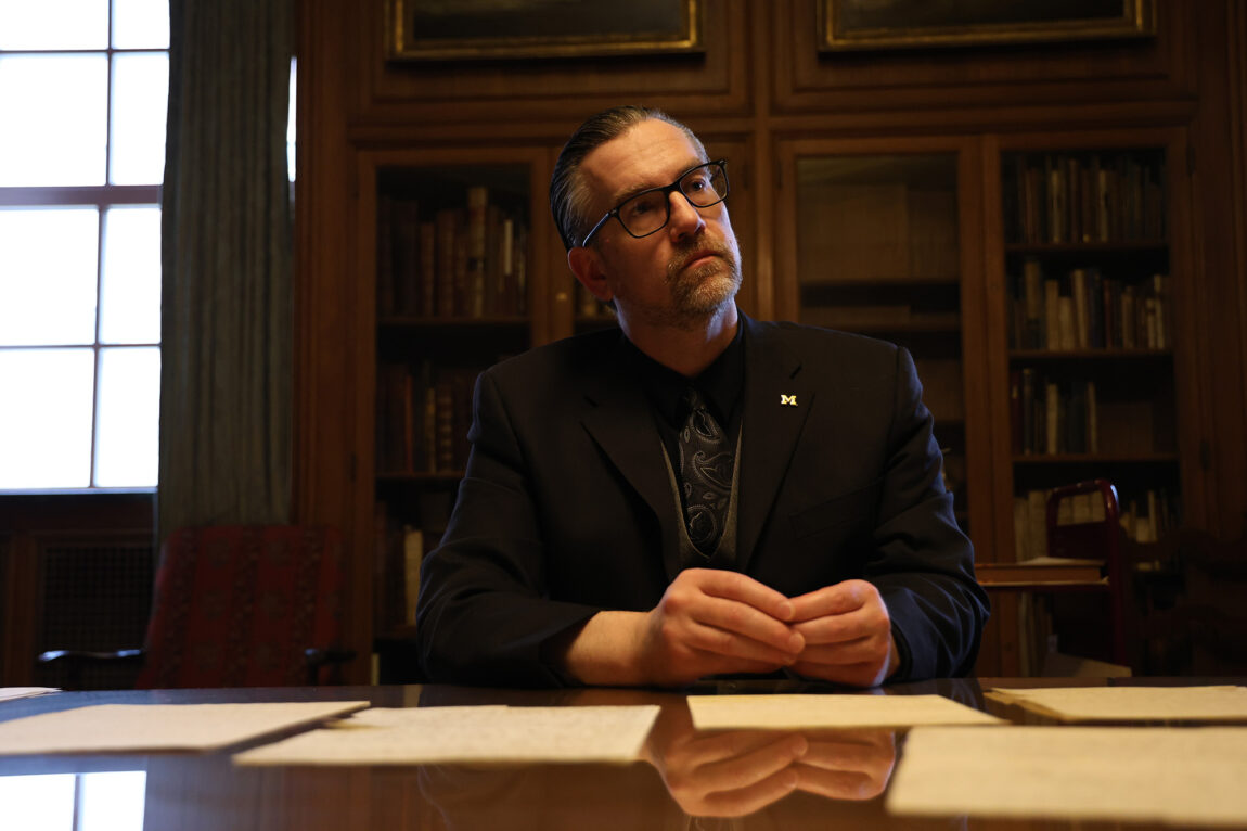A man at a desk upon which sit historic papers