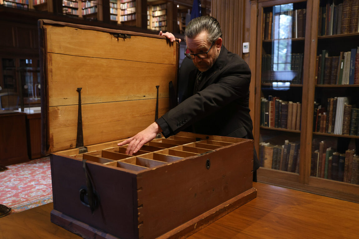 A man opening a large trunk from the 1700s
