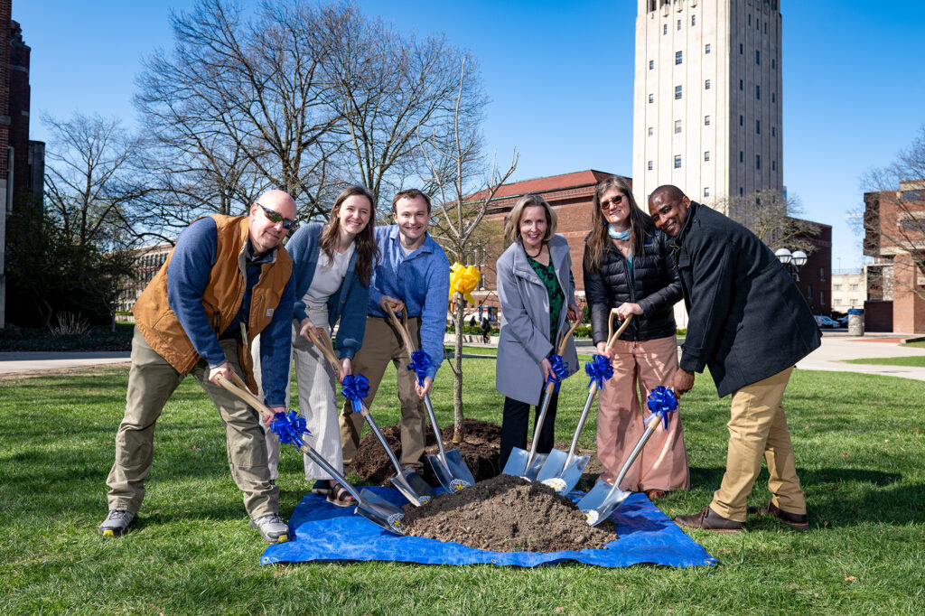 People standing with shovels in the dirt at the site of a tree planting ceremony