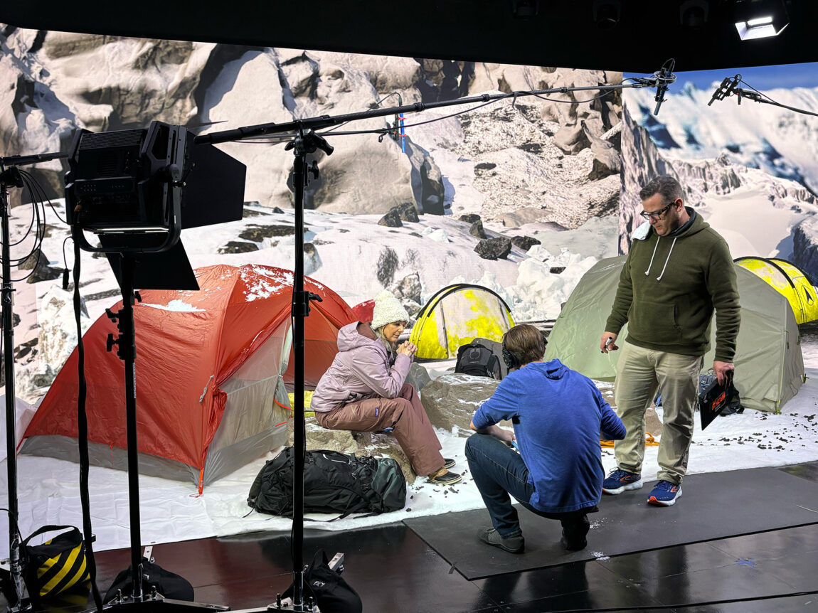Three people preparing to film a scene for an online course that centers around an expedition to Mount Everest