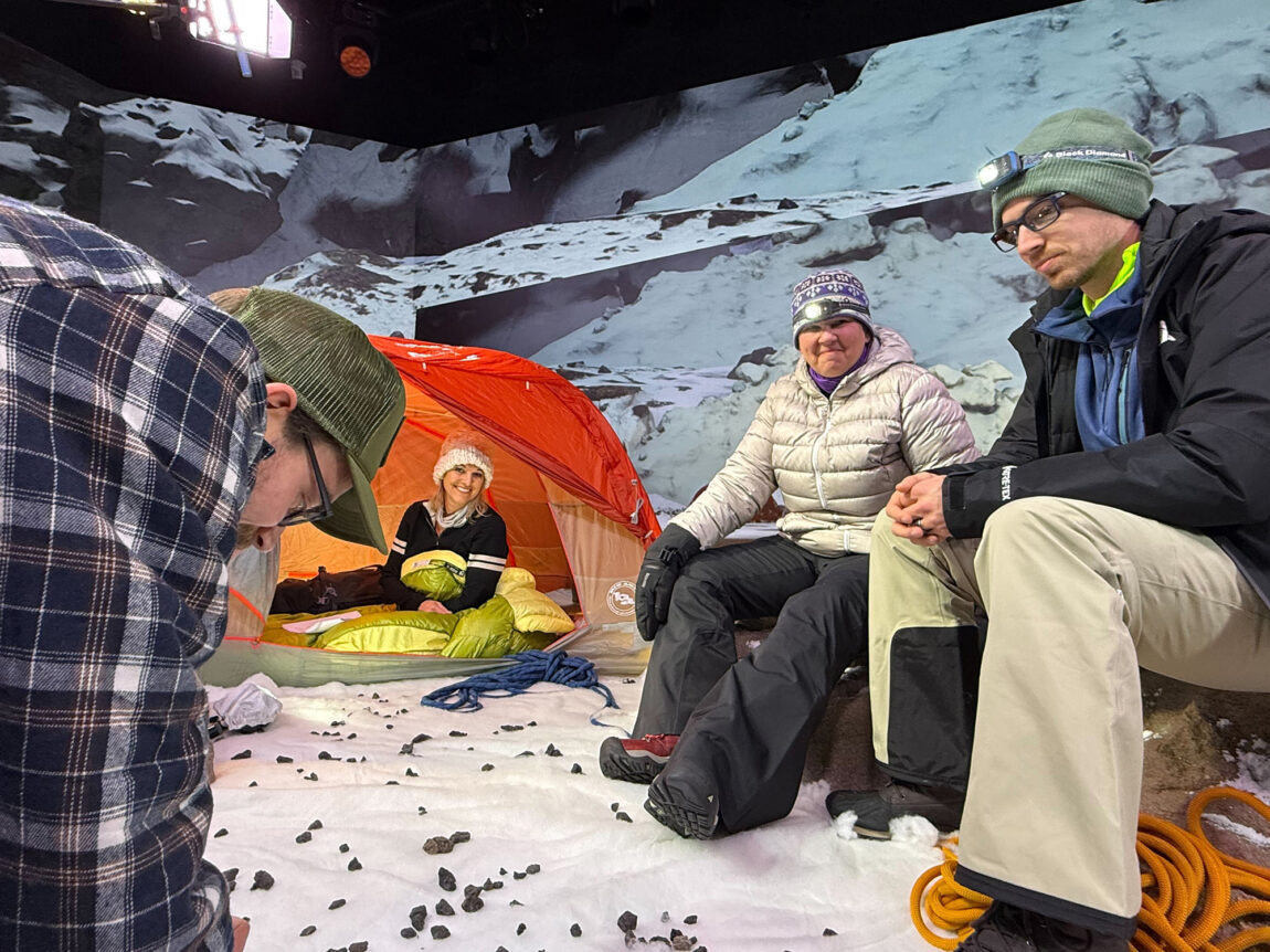 People sitting and waiting to film a scene for an online course centered around an expedition to Mount Everest
