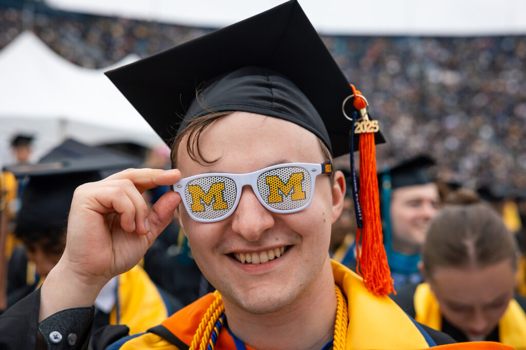 A man wearing sunglasses with two block Ms on the lenses.