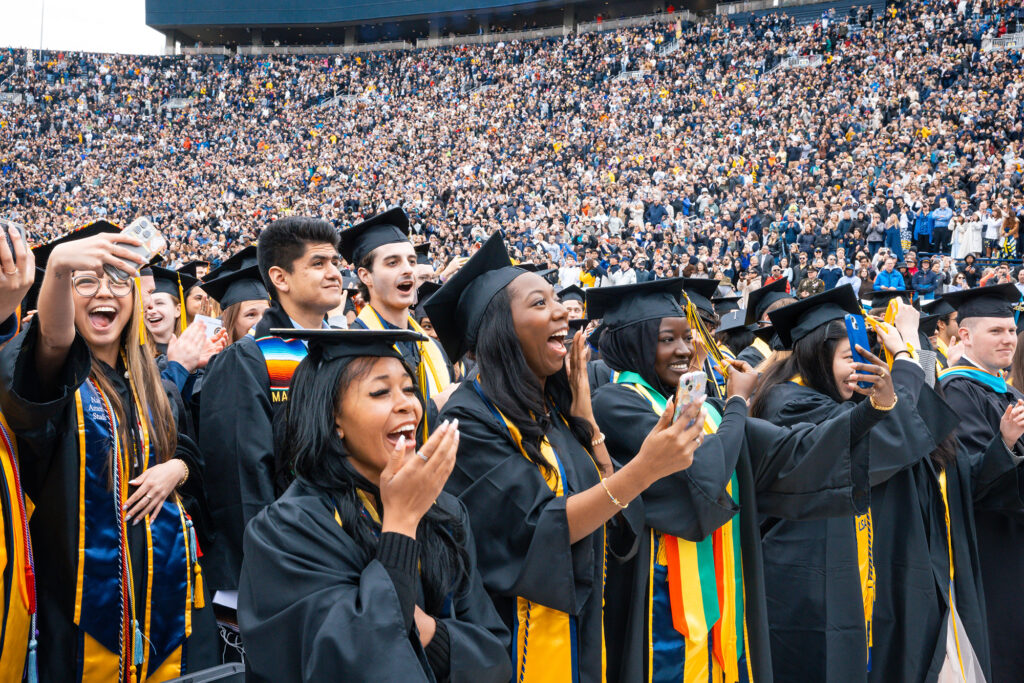 Several people laughing while standing at a graduation ceremony
