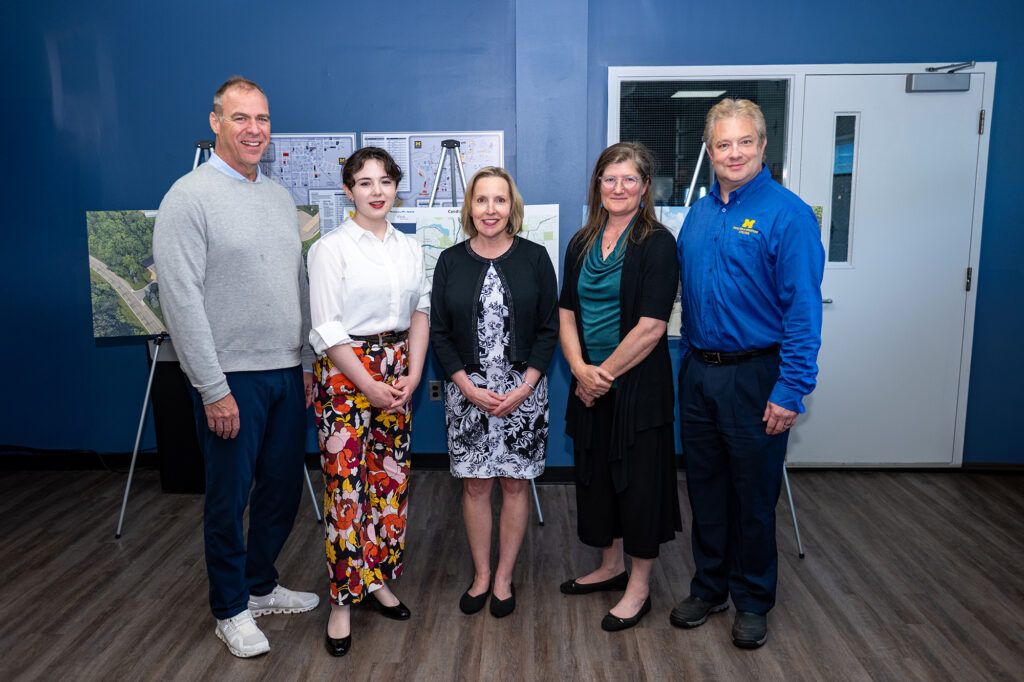 Five people standing and smiling