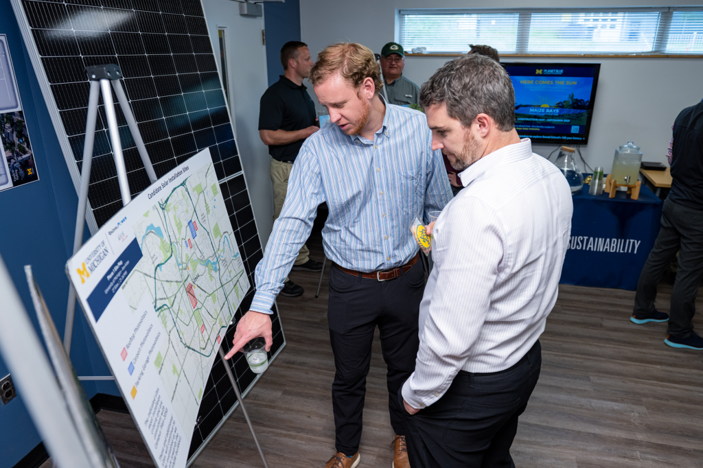 Two men standing at a poster board talking