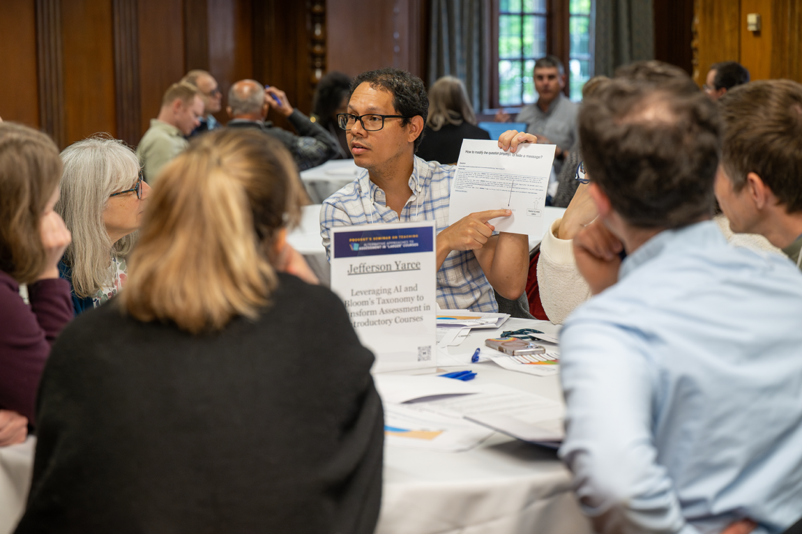 People sitting at a table looking at one person pointing to a piece of paper