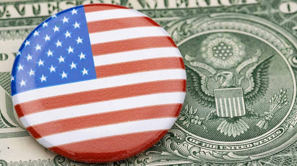 A button with an American flag sits on a $1 bill. Image credit: Marek Studzinski, Unsplash