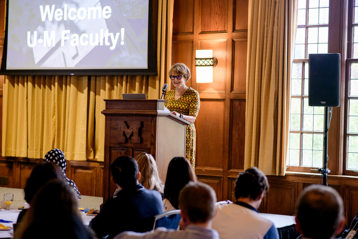 A woman addresses a crown from a lectern