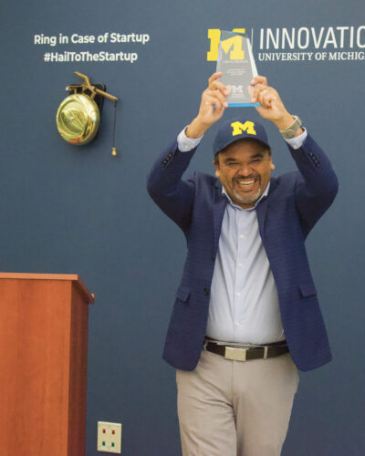 A man smiles while holding up a trophy