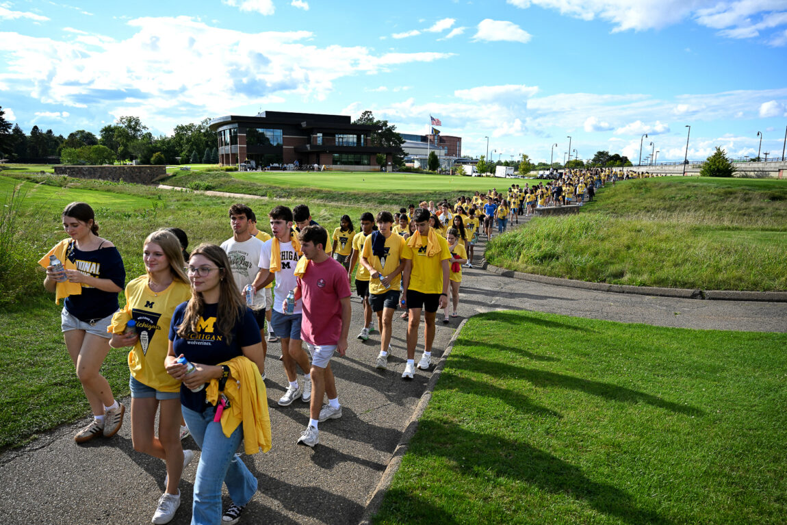 Students walk to the University of Michigan Golf Course for a tailgate