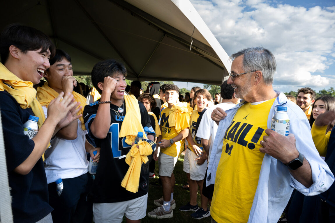 A man shows off his "HAIL" T-shirt to students who cheer