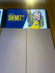 Sunny Shemet has her own locker in the U-M Women's Baksetball team lockeroom. Sunny's name and photo, featuring maize-and-blue pom poms is affixed to the top of the locker.