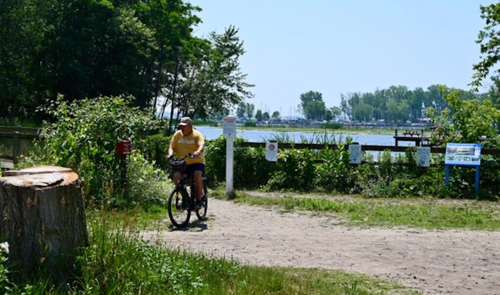 A man rides his bike along the Wilder River Walk at the Muskegon Lake Nature Preserve. The site had been a literal dump before being restored. Image credit: Greta Guest, Michigan News