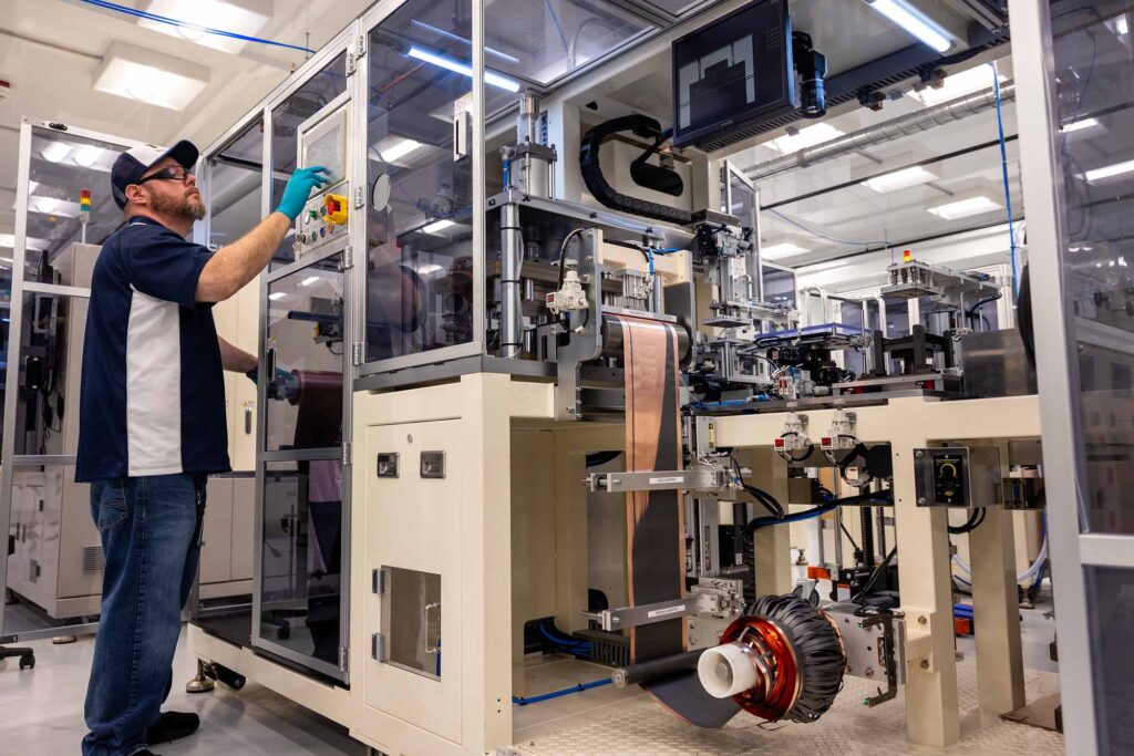 Man operating an electrode punching machine in a modern lab.
