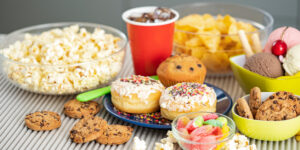 Plate of junk food includes soda, popcorn, donuts, and candy.