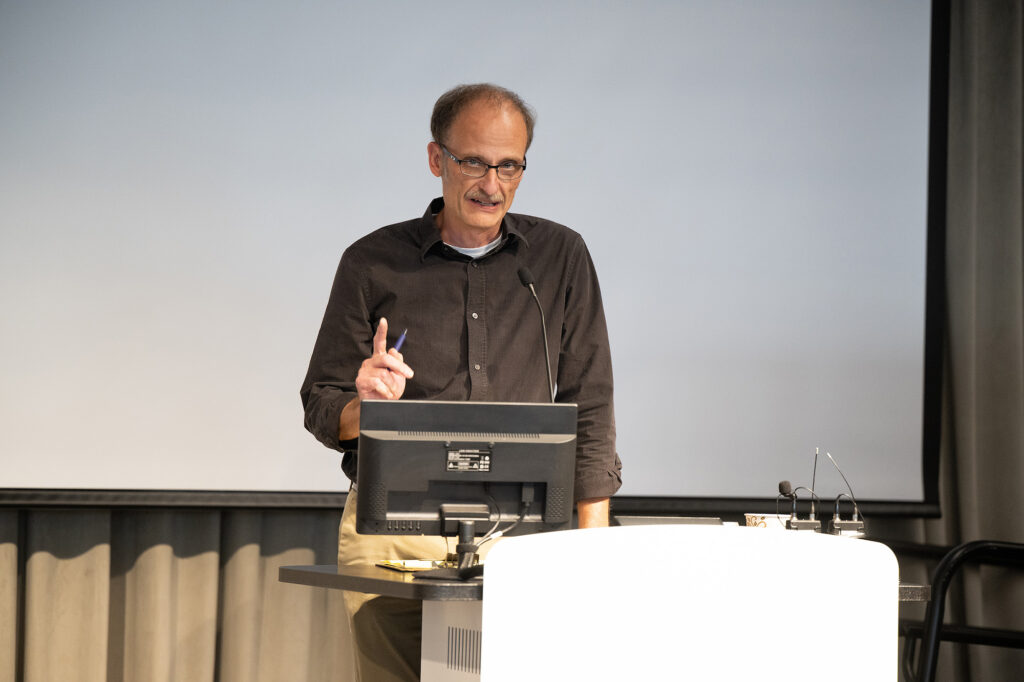 A man raises his finger while speaking to a crowd